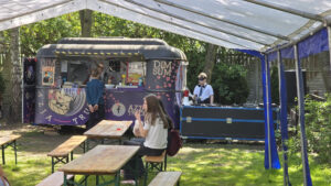 Festiwal Rubik's Madness: food truck z dim sum, DJ i ludzie przy stołach na zewnątrz.
