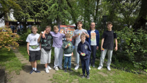 Grupa młodych ludzi z kostkami Rubika na tle plakatu "Rubik's Madness