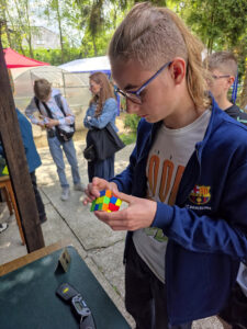 Młody mężczyzna rozwiązuje kostkę Rubika na wydarzeniu Rubik’s Madness 2026.