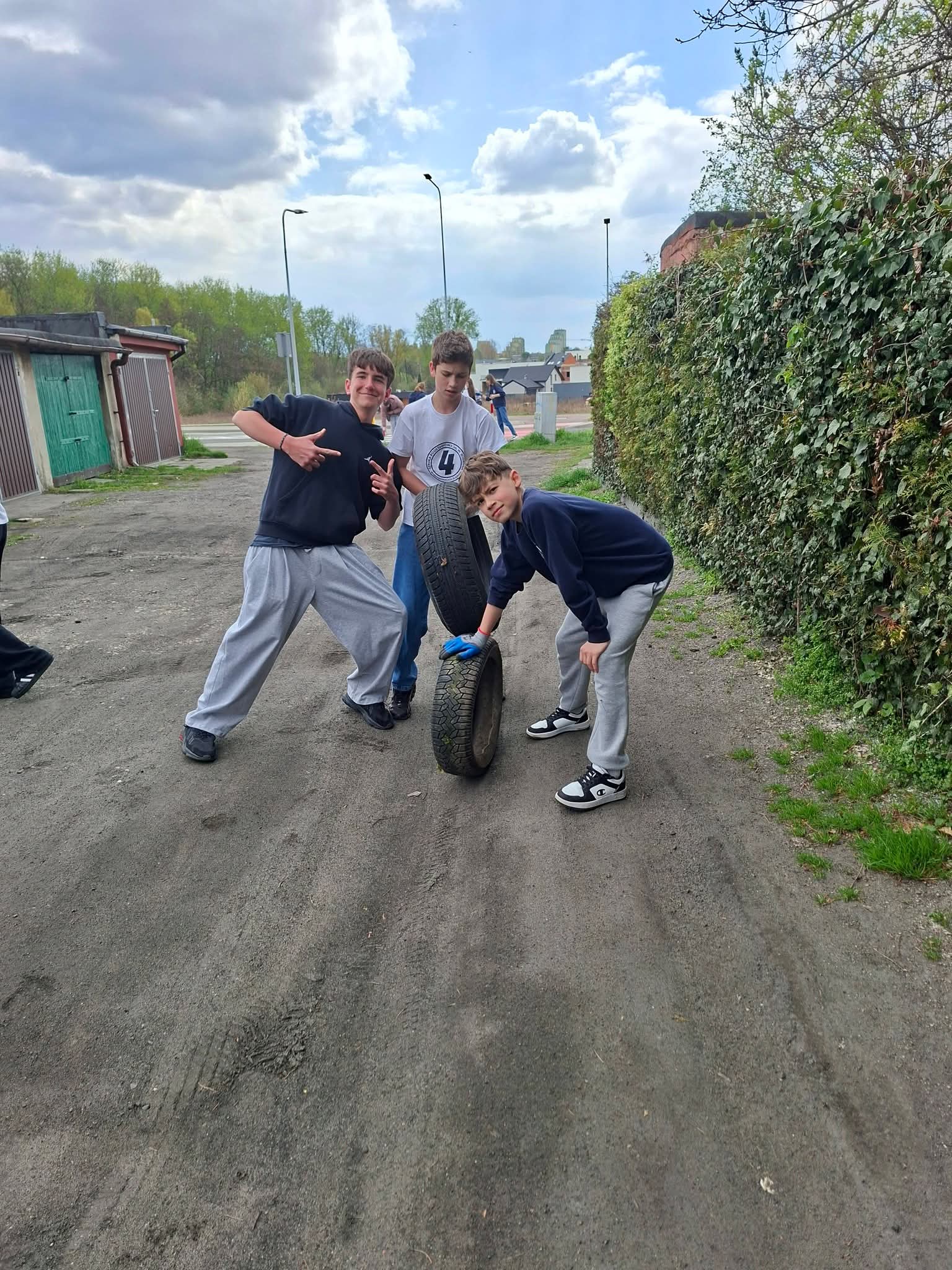 Trzech chłopców bawi się oponą na podwórku.