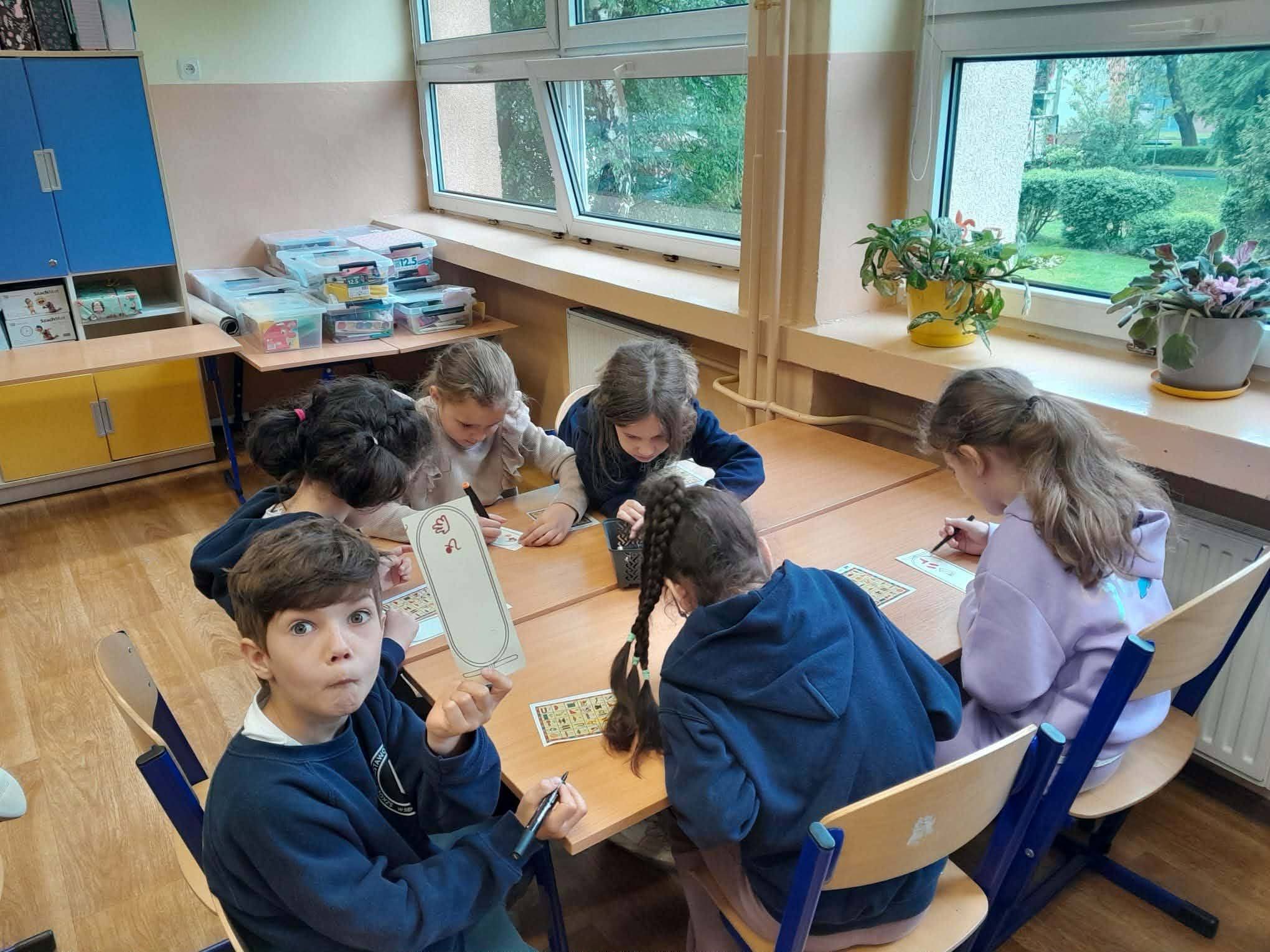 Dzieci grają w grę planszową przy stole w klasie.