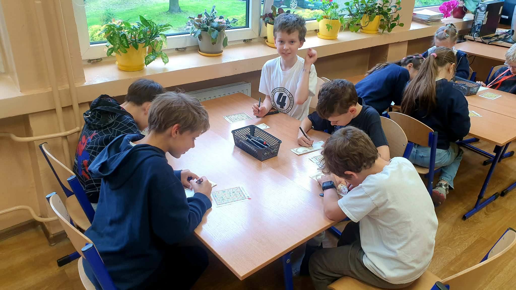 Dzieci grają w gry planszowe przy stole w sali lekcyjnej.