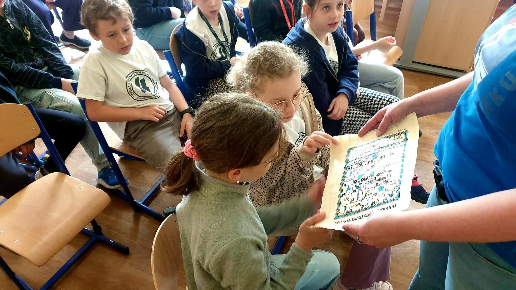 Dzieci patrzą na papirus z hieroglifami, ucząc się o starożytnym Egipcie.