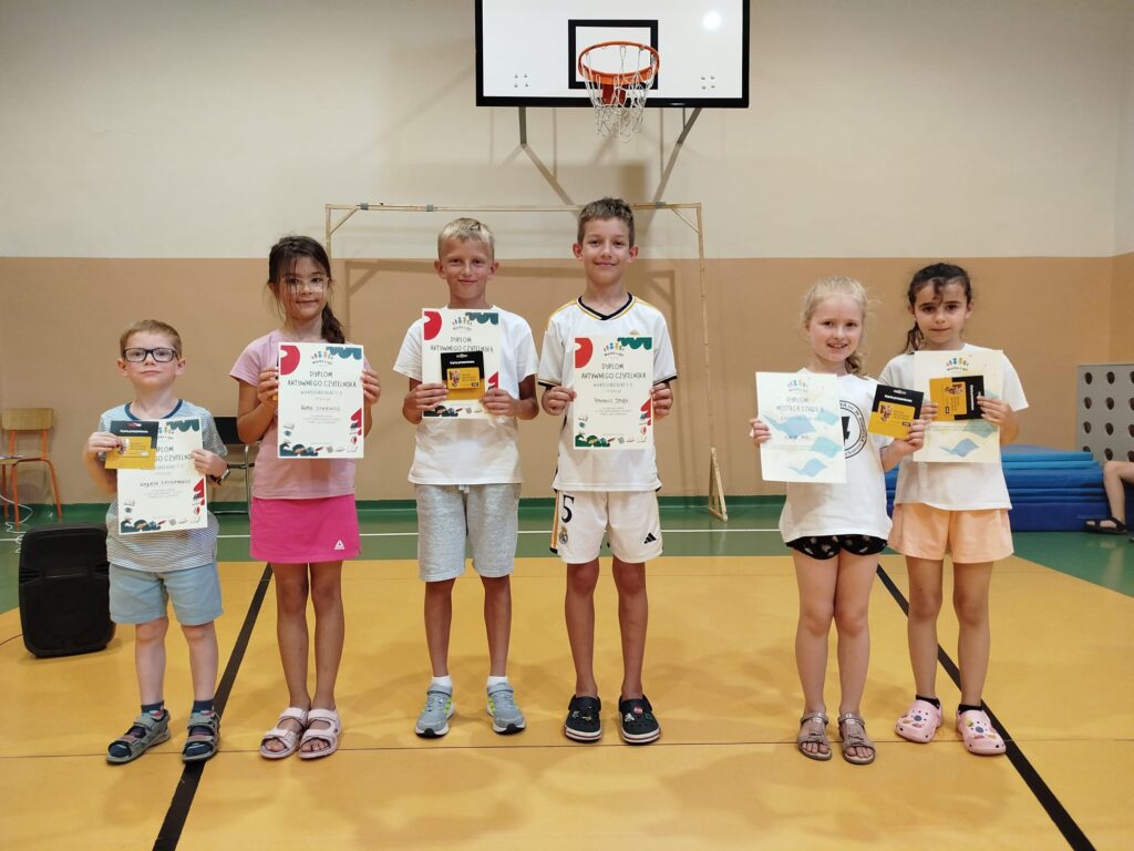 Sześć dzieci z dyplomami w sali sportowej