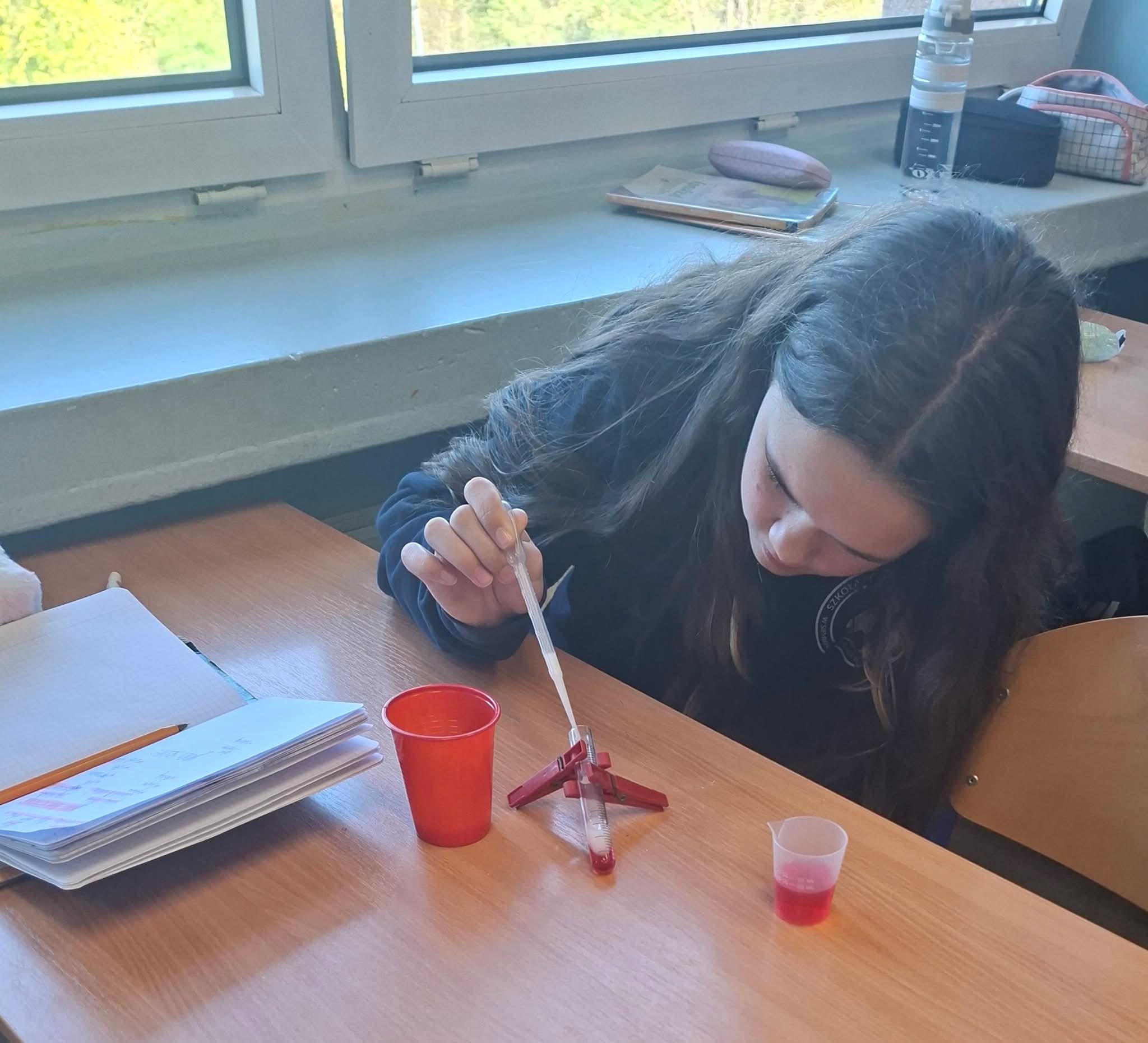 Dziewczynka przeprowadza eksperyment chemiczny z pipetą i probówkami.