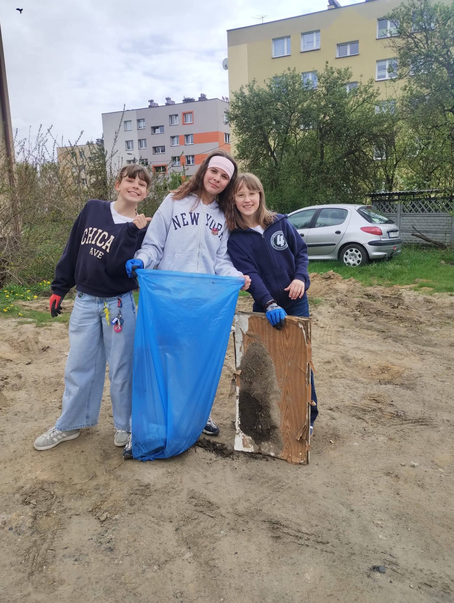 Trzy dziewczyny zbierają śmieci do niebieskiego worka