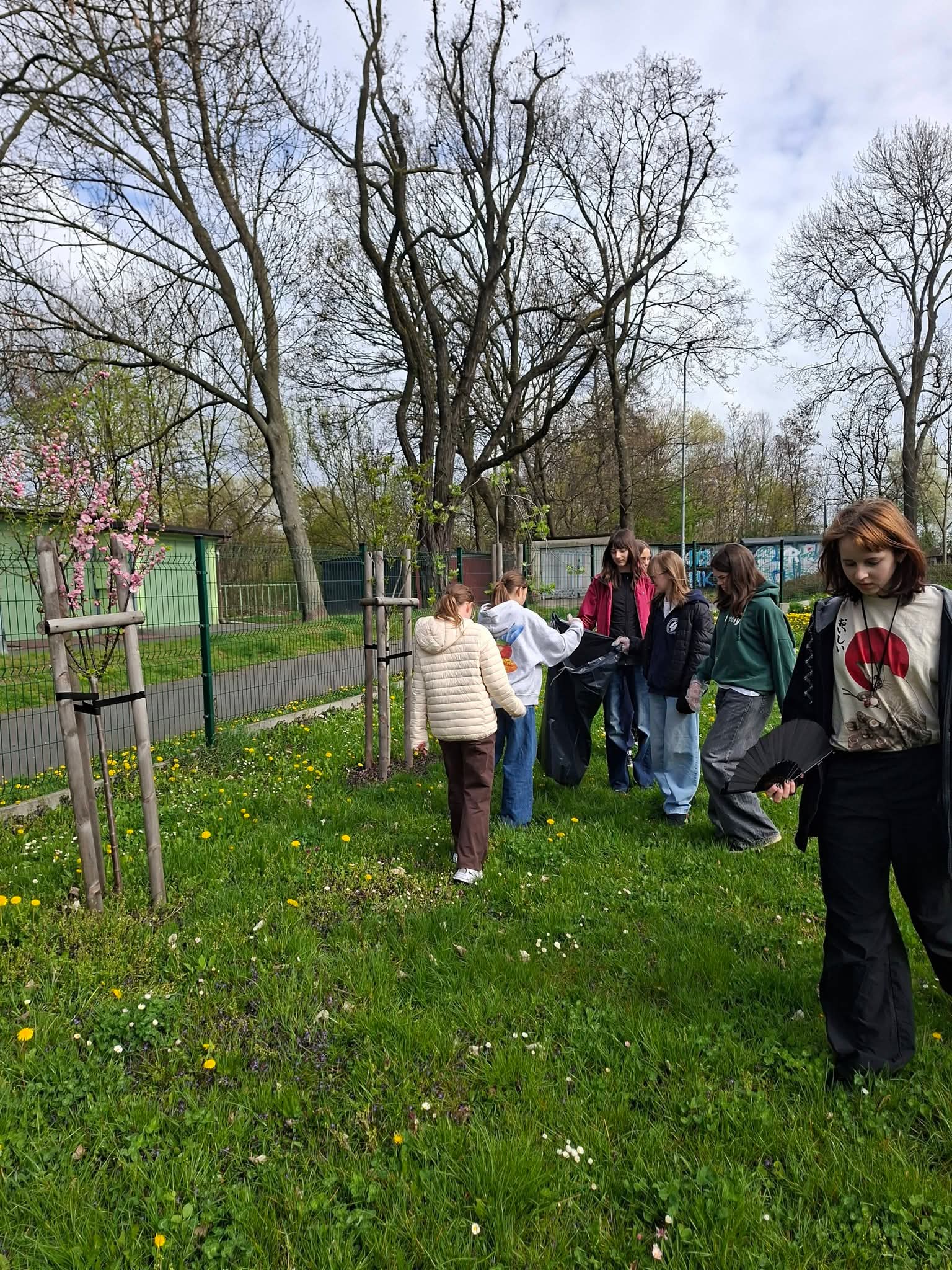 Grupa młodych ludzi sprzątająca park z workami na śmieci