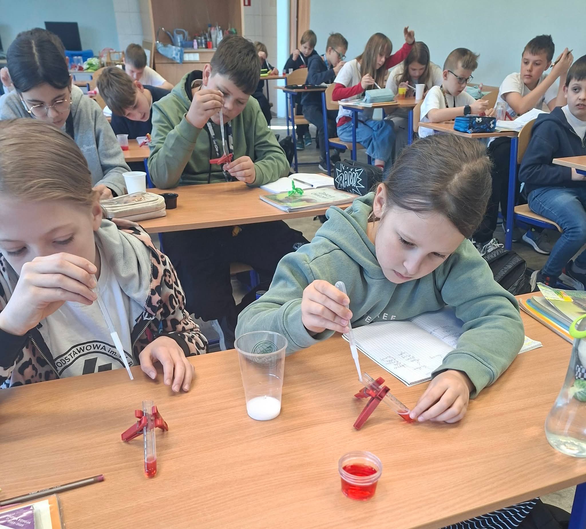 Uczniowie w szkole przeprowadzają eksperymenty chemiczne z probówkami.