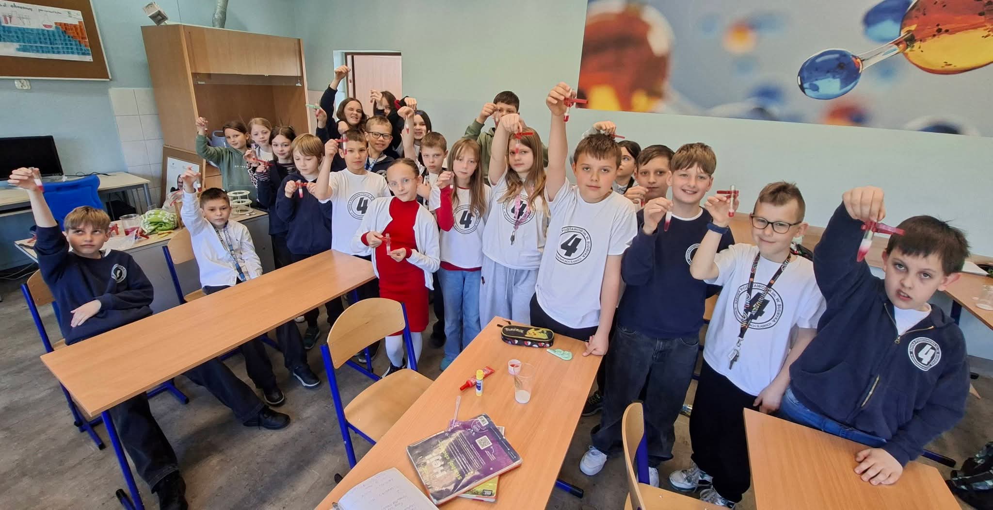 Uczniowie trzymają probówki z czerwonym płynem podczas lekcji chemii.