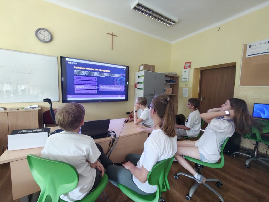 Uczniowie oglądają prezentację o psychologii na dużym ekranie w sali lekcyjnej