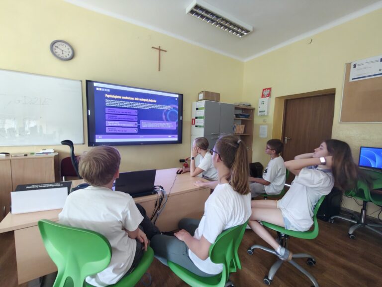 Uczniowie oglądają prezentację o psychologii na dużym ekranie w sali lekcyjnej